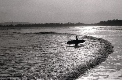 Un surfista entrando al mar con su tablón